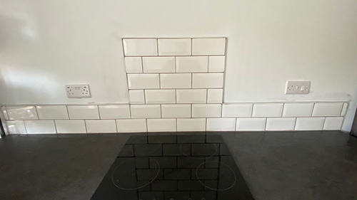 a kitchen countertop with a white tiled wall