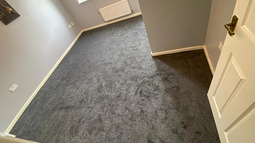 a grey, newly fitted carpet in an empty room