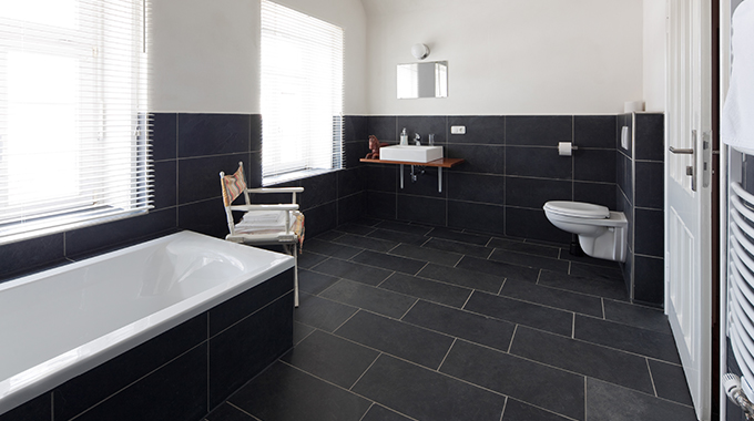 a bathroom with black tiles across the floor and halfway up the wall