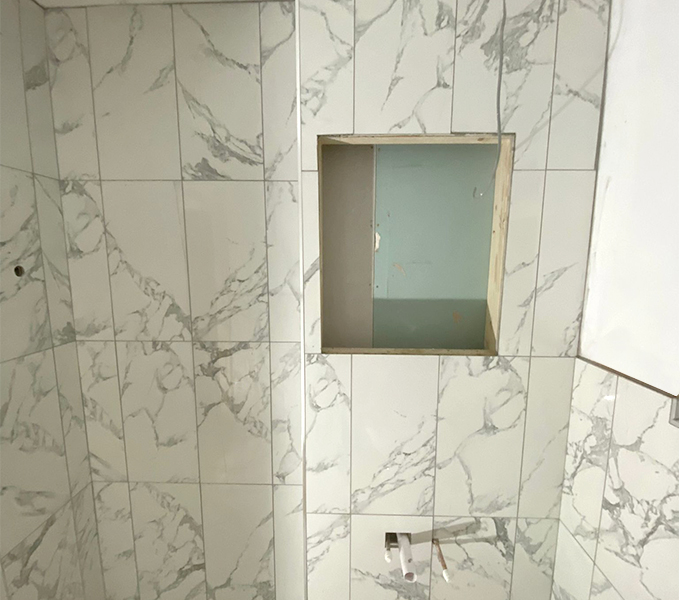 a bathroom in the middle of renovation with white marble-patterned tiles
