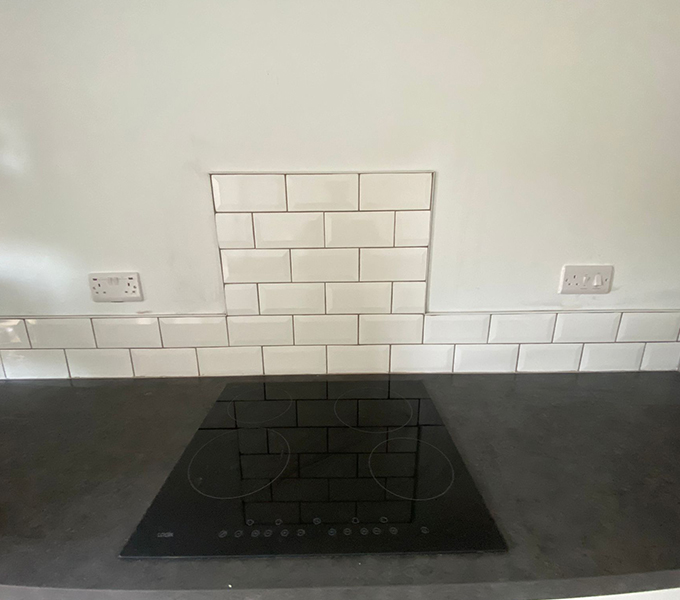 a kitchen countertop with a two layer wall tiling, with the tiles being six layers above the hob