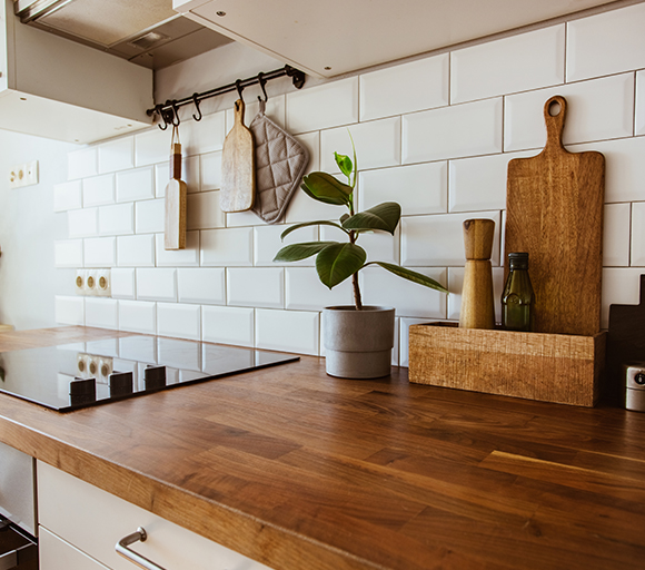 a kitchen with large white kitchen tiles on the wall above a rustic kitchen countertop 