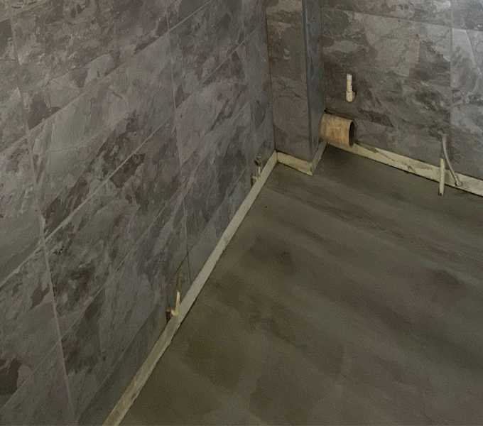 a tiled wall with a vinyl flooring in a room under renovation